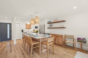 A modern kitchen with wooden flooring, a central island, and pendant lighting. - Walk to Lido Beach & St. Armands! Heated Pool/Spa (Sarasota)