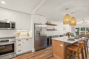 A modern kitchen with white cabinetry, stainless steel appliances, and a central island with seating.