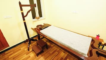A room with a wooden examination table and stool, featuring a window above.