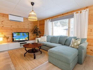 A cozy living room with a sectional sofa, a television, a wooden ceiling, and a large window. - Brofeldt by Interhome (Tohmajärvi)