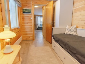 Un intérieur en bois avec un lit, une lampe et une vue sur une pièce où se trouve un canapé.