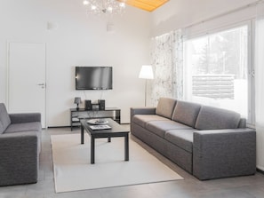 Un salon moderne avec un canapé, une table basse, un téléviseur et une lampe.
