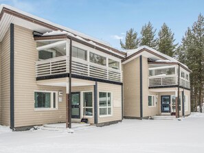 A two-story building with a balcony, large windows, and a snow-covered ground.