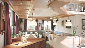 Un'accogliente sala da pranzo con mobili in legno, lampade a sospensione e un'ampia finestra che offre luce naturale.