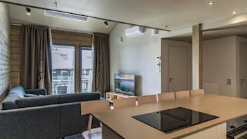 A modern kitchen with a central island, a built-in oven, and a dining area with a table and chairs.