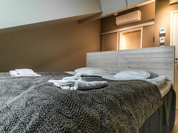 Un lit bien fait, avec une couvre-lit à motifs, des oreillers et des serviettes pliées.