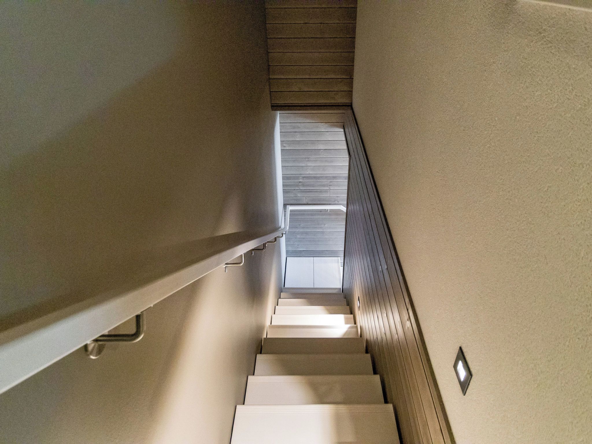 A staircase with a handrail and a landing area with a light fixture.