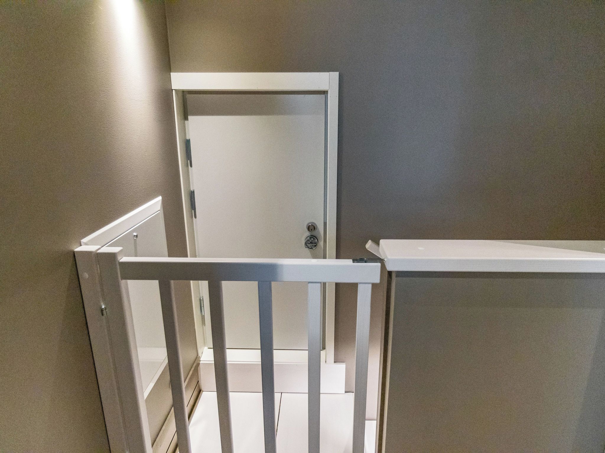 A room with a white door, a white railing, and a beige wall.