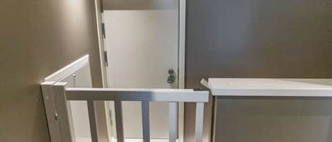 A room with a white door, a white railing, and a beige wall.