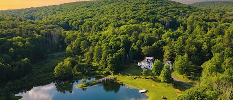 A lush green landscape with a lake, a house, and a golf course.