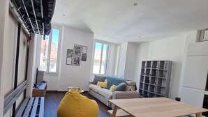 Una sala moderna con un banco de madera, un sillón de pelota amarillo, una mesa de madera y un sofá gris.
