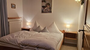 A neatly made bed with two pillows, a bedside table with a lamp, and a framed picture on the wall. - Ferienwohnung Zuahaisl für 4 Personen, 2 Schlafzimmer mit Balkon, 70 m² (Inzell)