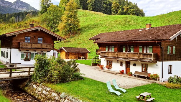 A traditional chalet-style building with a wooden facade, a balcony, and a stone pathway leading to the entrance. - Ferienwohnung Zuahaisl für 4 Personen, 2 Schlafzimmer mit Balkon, 70 m² (Inzell)