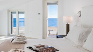A hotel room with a bed, a bedside lamp, a view of the sea, and a door leading to a balcony. - Stunning private villa with WIFI, private pool, A/C, TV, patio, panoramic view, close to Syracuse (Plemmirio)