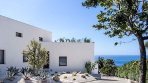 A modern building with a white facade, a garden with cacti and succulents, and a view of the sea. - Stunning private villa with WIFI, private pool, A/C, TV, patio, panoramic view, close to Syracuse (Plemmirio)