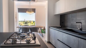 Eine moderne Küche mit einem Gasherd, dunklen Schränken und Blick durch ein Fenster.