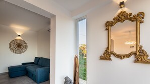 Ein modernes Wohnzimmer mit einem blauen Sofa, einem Wandkunstwerk und einem großen, verzierten Spiegel.