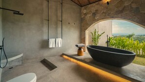 A modern bathroom with a stone wall, a large black sink, a toilet, and a shower area. - SIVANA, Hotel Boutique with ocean or garden views - Adults only (Pecatu)