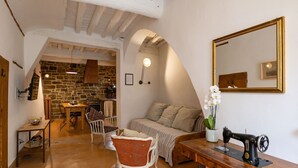 A cozy living room with a stone wall, wooden furniture, a sewing machine, and a large mirror.