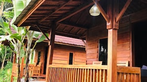 A wooden cabin with a porch, surrounded by lush greenery. - Serenity Lodge Tetebatu Lombok (Tetebatu)