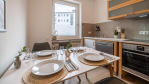 Cocina moderna con comedor para cuatro personas. Incluye lavavajillas, horno y ventana con vistas a edificios.