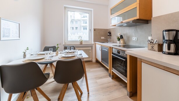 Una cocina moderna con armarios de madera, horno integrado y cafetera.