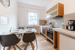 A modern kitchen with wooden cabinets, a built-in oven, and a coffee maker.