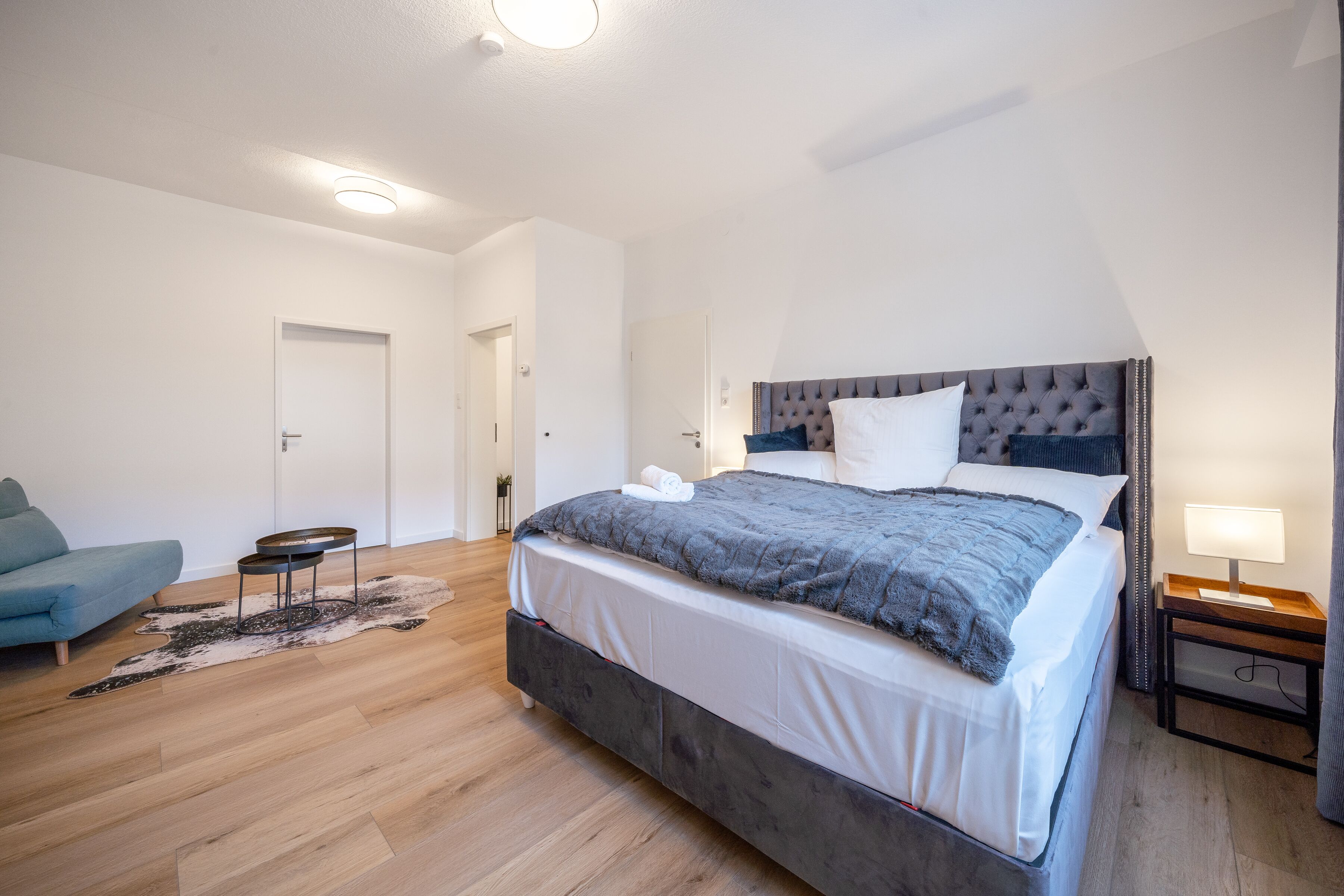 Une chambre à coucher moderne avec un grand lit, un canapé, une petite table et une table de chevet.