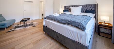 Une chambre à coucher moderne avec un grand lit, un canapé, une petite table et une table de chevet.