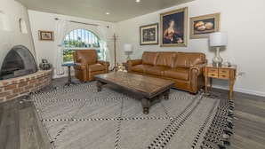 A living room with a fireplace, leather sofa, and a patterned rug.