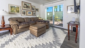 A living room with a sectional sofa, a ceiling fan, and a large window.