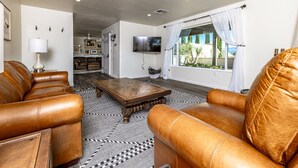 A living room with leather sofas, a wooden coffee table, and a TV mounted on the wall.