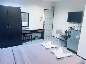 A hotel room with a bed, a desk, a chair, a television, and a minibar. - Apartment X5 (Pattaya)