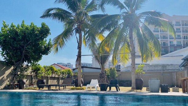 A swimming pool with lounge chairs and palm trees. - Apartment X5 (Pattaya)