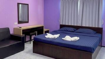 A hotel room with a bed, a desk, a chair, and a window with curtains.