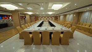 A conference room with a long table, beige chairs, and a buffet area in the background. - Hotel Sura Grand (Siliguri)