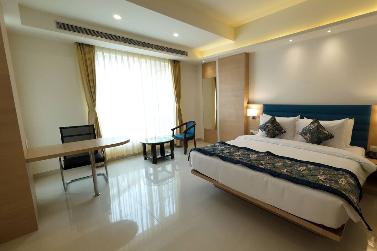 A modern hotel room with a large bed, bedside tables, a desk, and a chair.