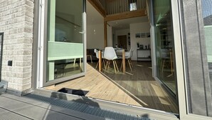 Un interior moderno con comedor, cocina y un balcón con suelo de madera.