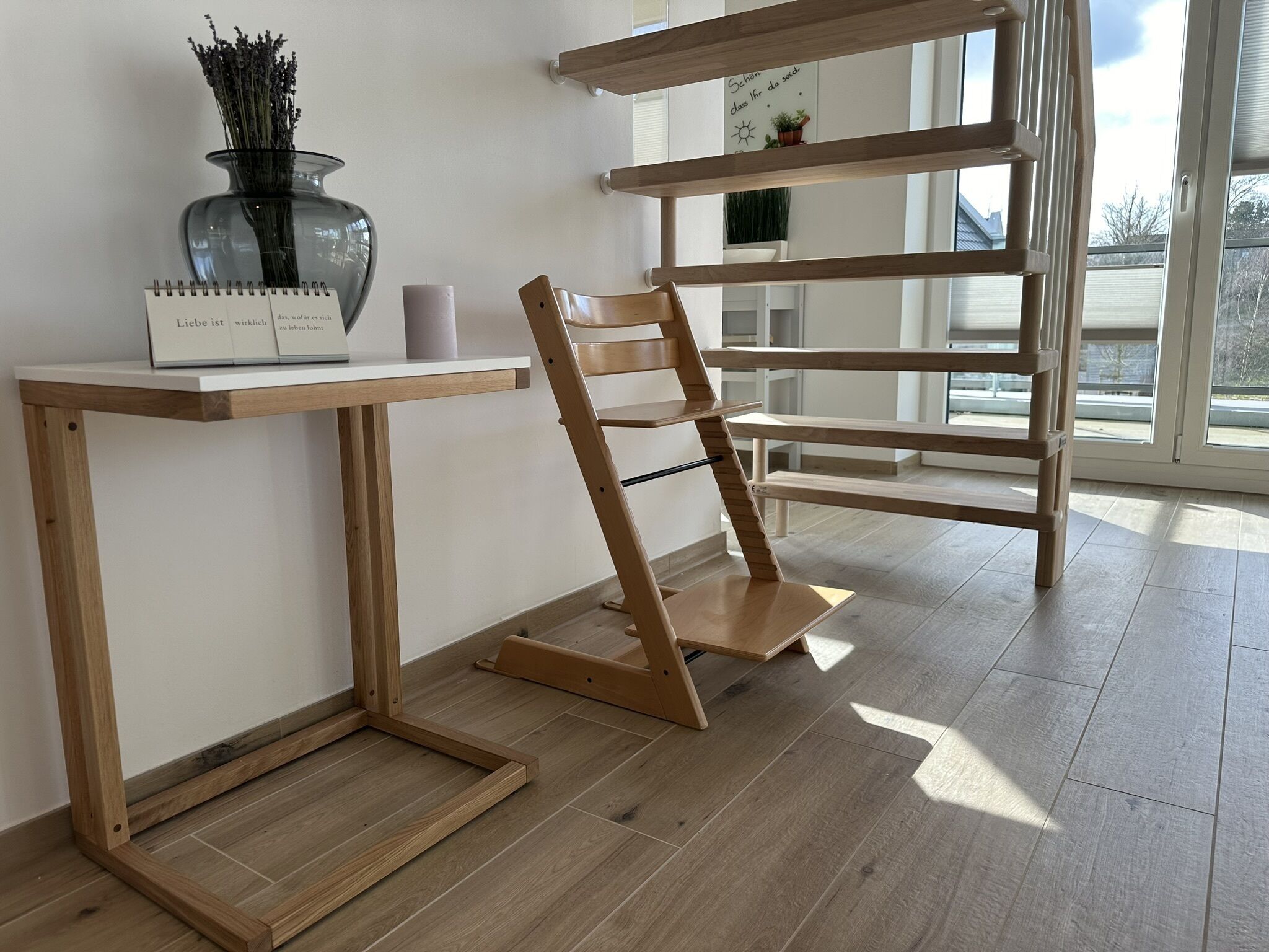 Une pièce avec un bureau en bois, un tableau blanc où sont inscrites des citations inspirantes, un vase de lavande et une fenêtre donnant sur l’extérieur.