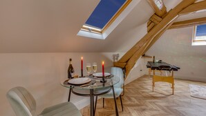 A dining area with a glass table, two chairs, candles, and a bottle of wine.
