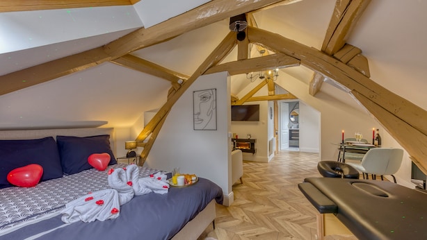 A cozy bedroom with a bed, a massage table, and a fireplace.