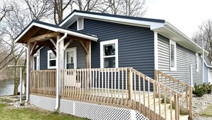 A two-story house with a wooden deck and a white picket fence. - Kayaks | Relax by River | 10 Min to Shipshewana | (Howe)