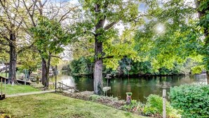 A riverside campsite with a wooden dock, grassy areas, and dense trees. - Kayaks | Relax by River | 10 Min to Shipshewana | (Howe)