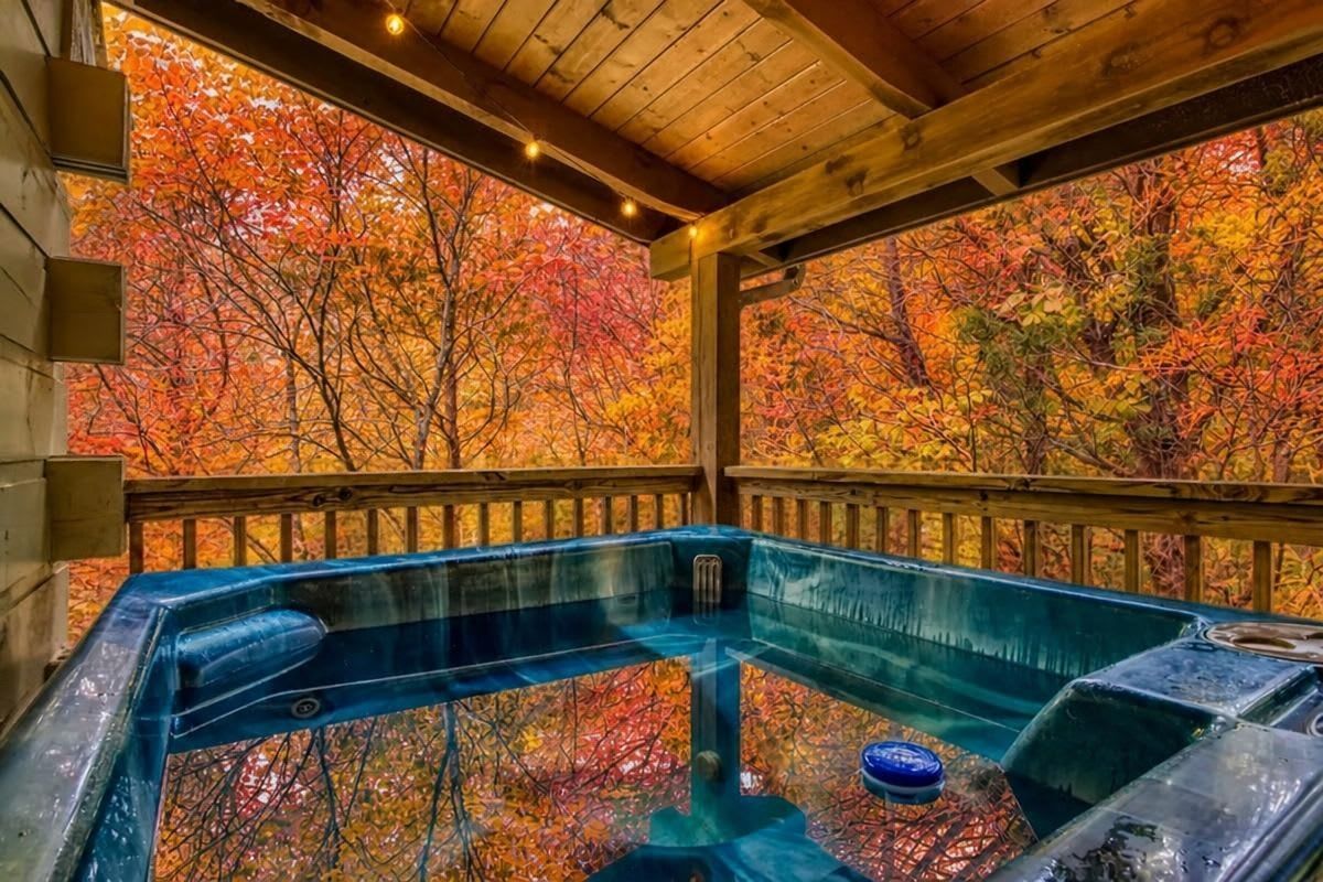 A hot tub area with a wooden deck and a view of autumn foliage.