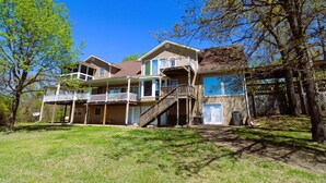A two-story house with a balcony, a covered porch, and a fenced yard. - Hummingbird Hideaway (Branson)