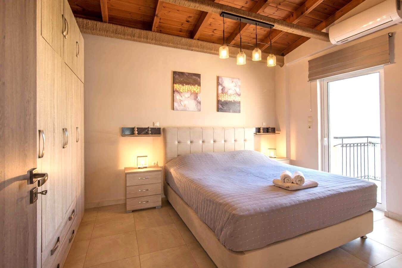Une chambre avec un grand lit, des tables de chevet, une armoire et un balcon.