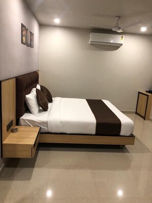 Una habitación de hotel moderna con una cama grande, una mesita de noche y un equipo de aire acondicionado en la pared.