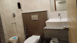 A compact bathroom with a toilet, sink, and shower. - Komfort Stay (Guwahati)