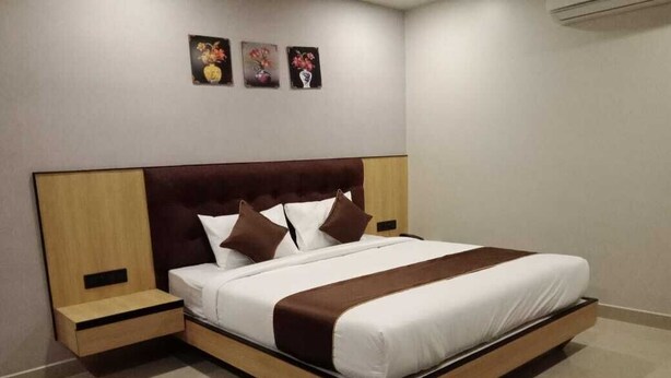 A modern hotel room with a large bed, wooden headboard, and two bedside tables. - Komfort Stay (Guwahati)