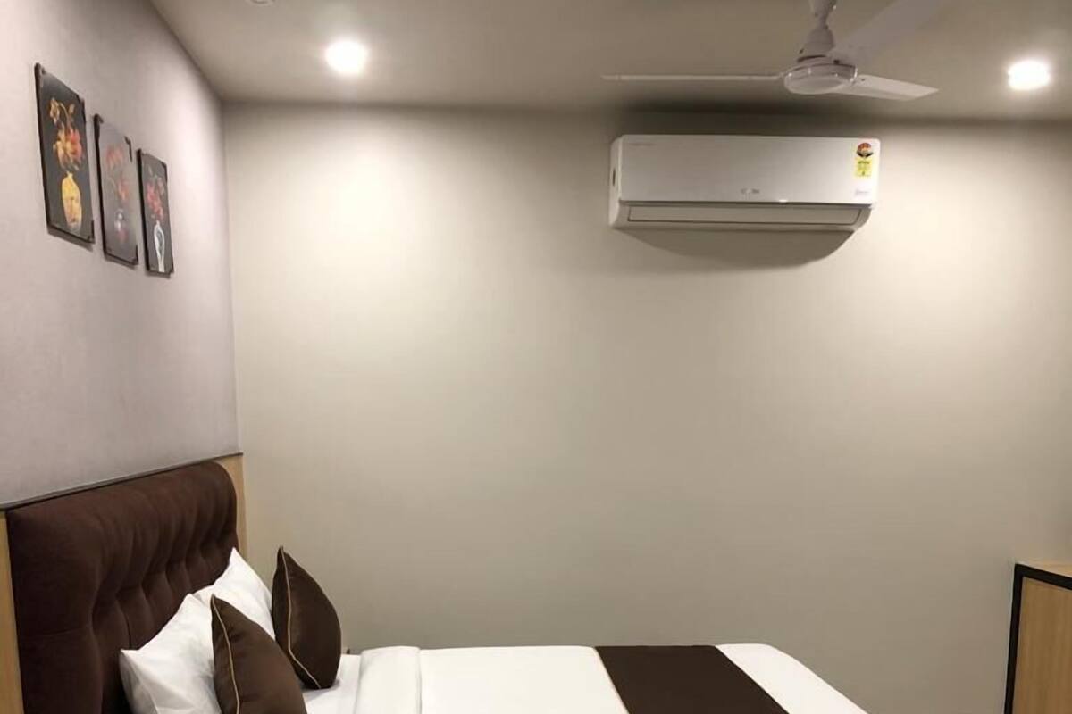 A modern bedroom with a bed, bedside tables, a fluffy rug, and an air conditioning unit.